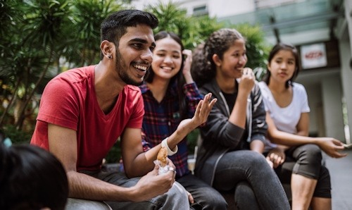 Students sat on bench eating and laughing