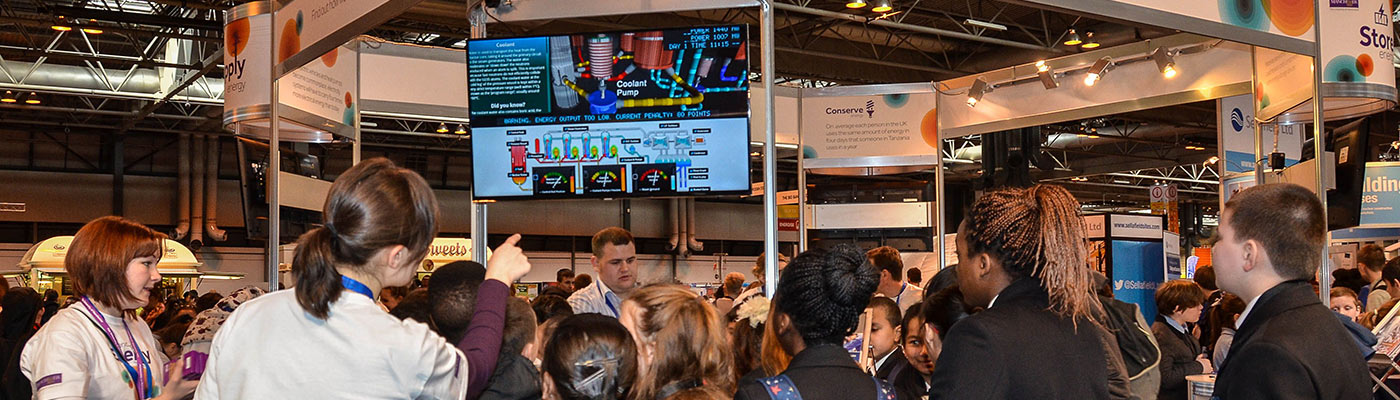 school students trying the nuclear reactor simulator game at a fair