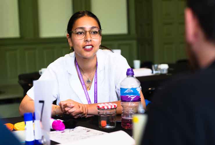 Aneeqa sat at a table with colourful props and talking to a student