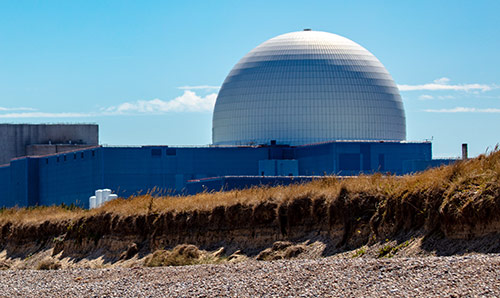 View of a nuclear power station with a pebble beach in the foreground

