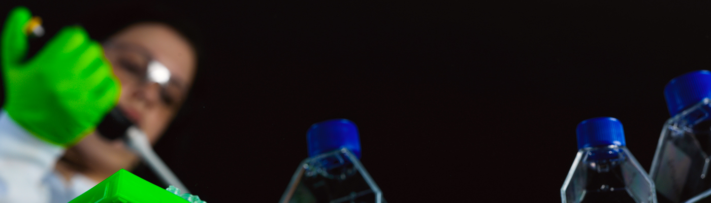 Worm's eye view of researcher squeezing pipette into bottle