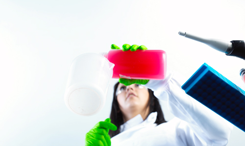 Researcher pouring pink liquid into a bottle