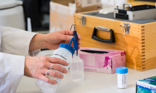 Anonymous hands squeezing content of plastic bottle into plastic container