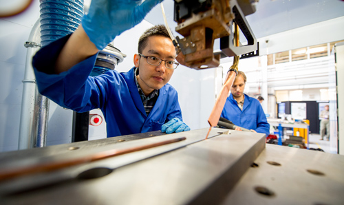 Researchers in blue lab coats focusing on operating equipment