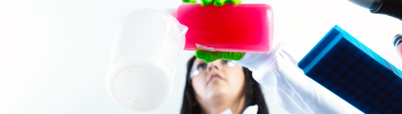 Researcher pouring pink liquid into a bottle