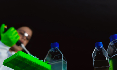 Worm's eye view of researcher squeezing pipette into bottle