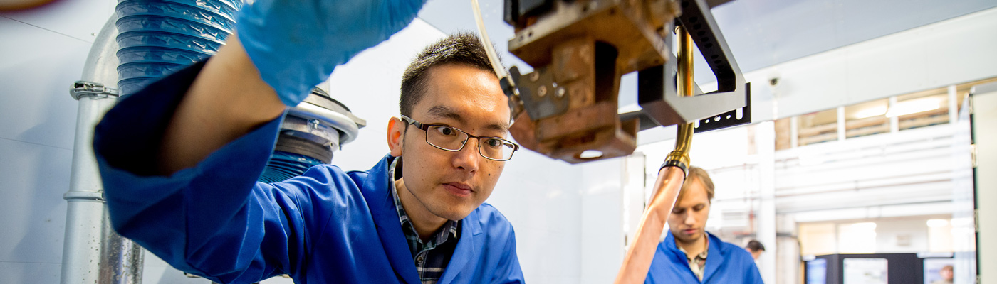 Researchers in blue lab coats focusing on operating equipment